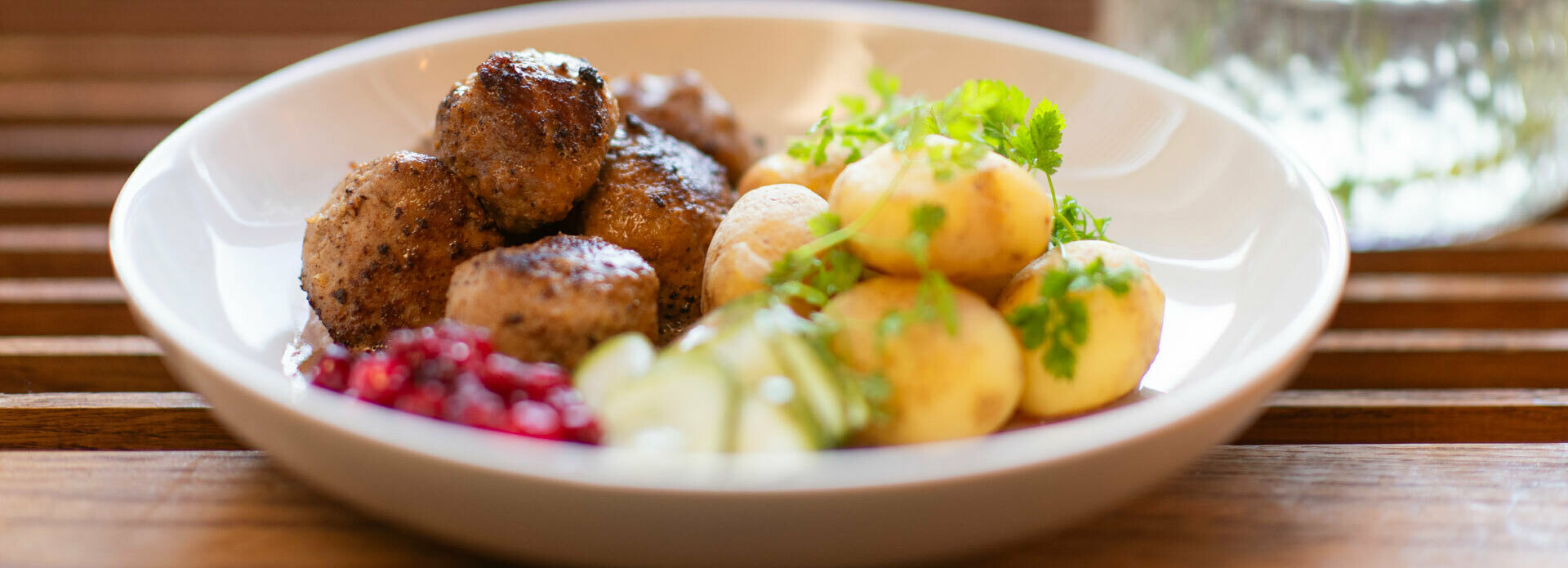 En tallrik med köttbullar, potatis, lingon pressgurka.