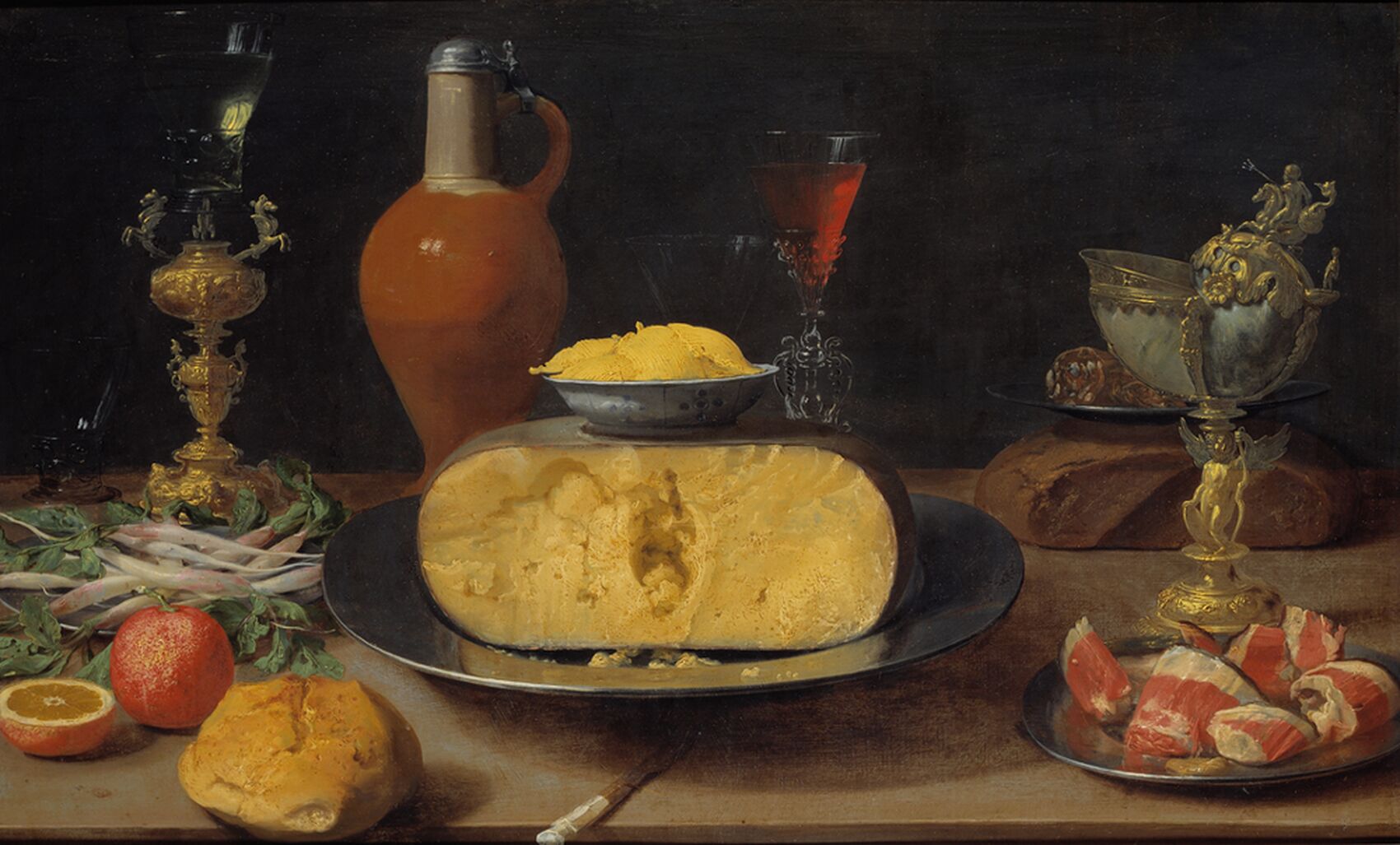 A table with cheese, orange, ham and goblets