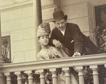 Äldre fotografi av en man och en kvinna som står och lutar sig mot en balustrad på en balkong eller terrass.